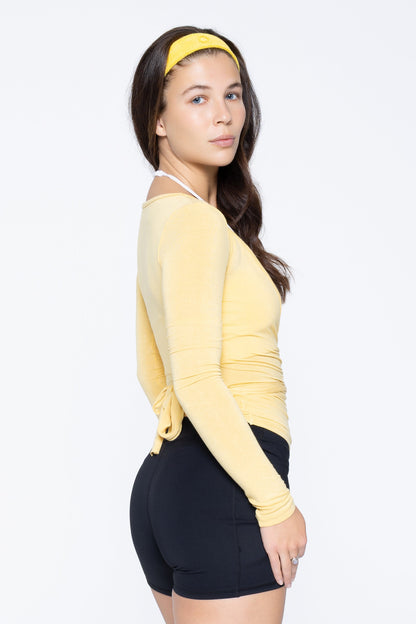 Side shot of model wearing Ruay Muse Reformer wrap top in yellow