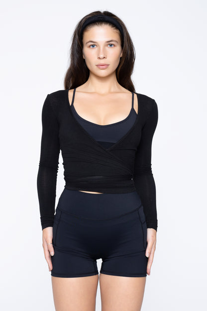 Close-up front shot of model wearing Ruay Muse Reformer Wrap Top in Eclipse navy