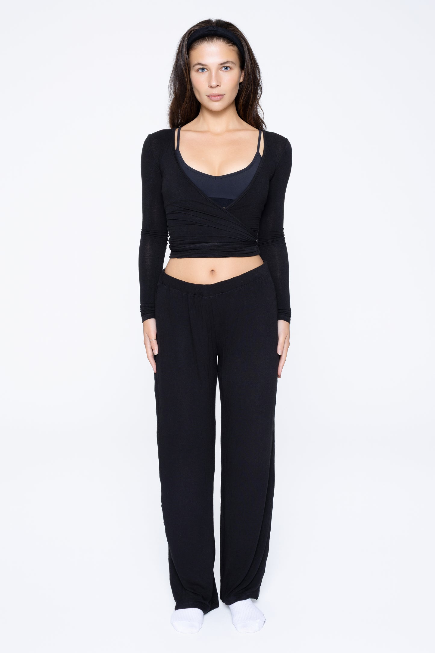 Front shot of model wearing Ruay Muse Reformer wrap top and trousers in black