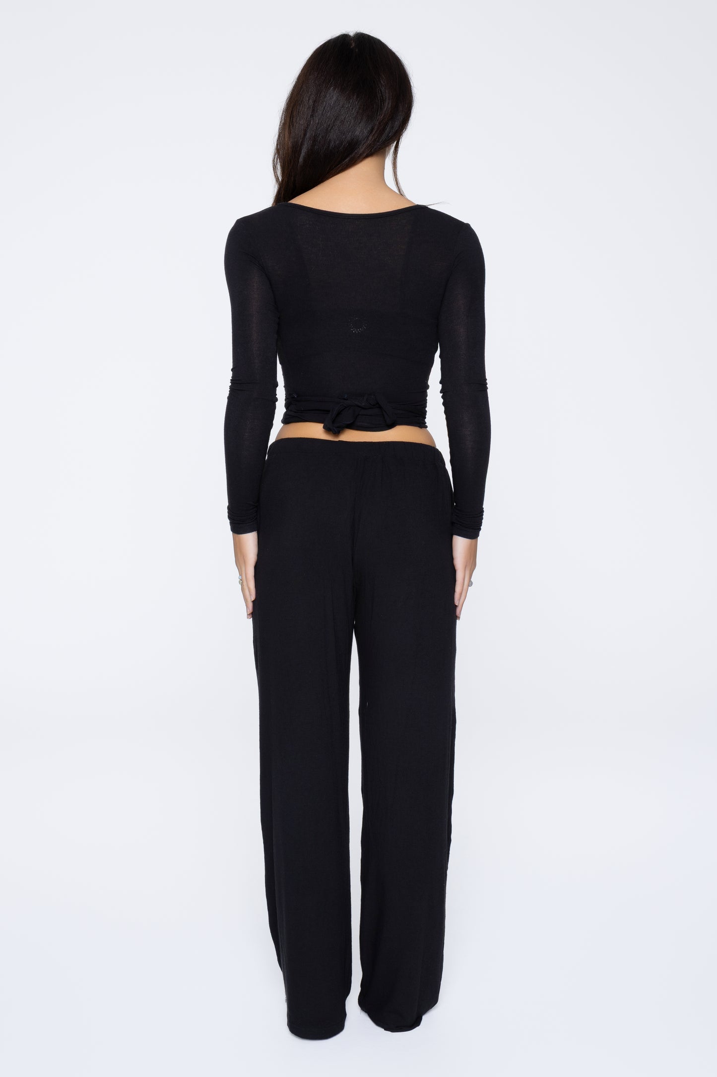 Back shot of model wearing Ruay Muse Reformer wrap top and trousers in black