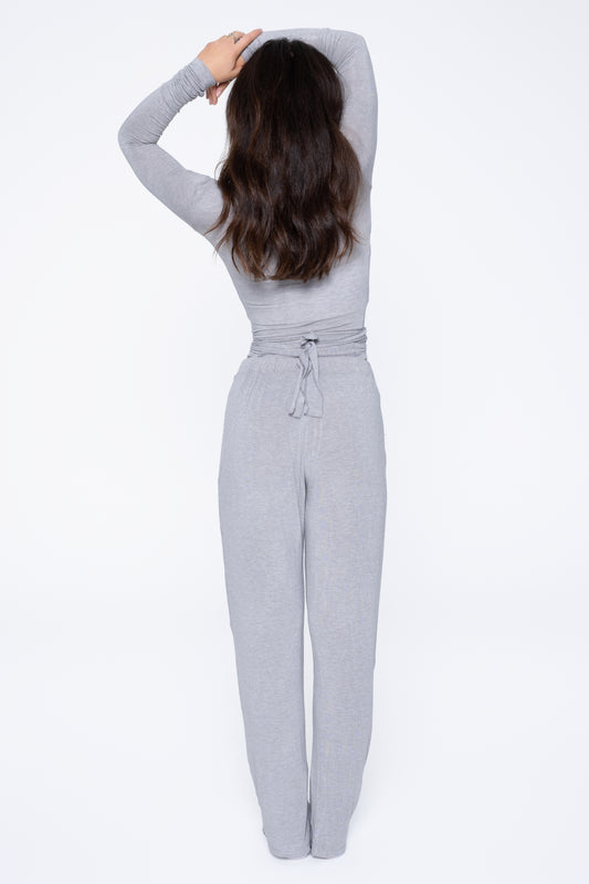Back shot of model wearing Ruay Muse Reformer wrap top and trousers in grey